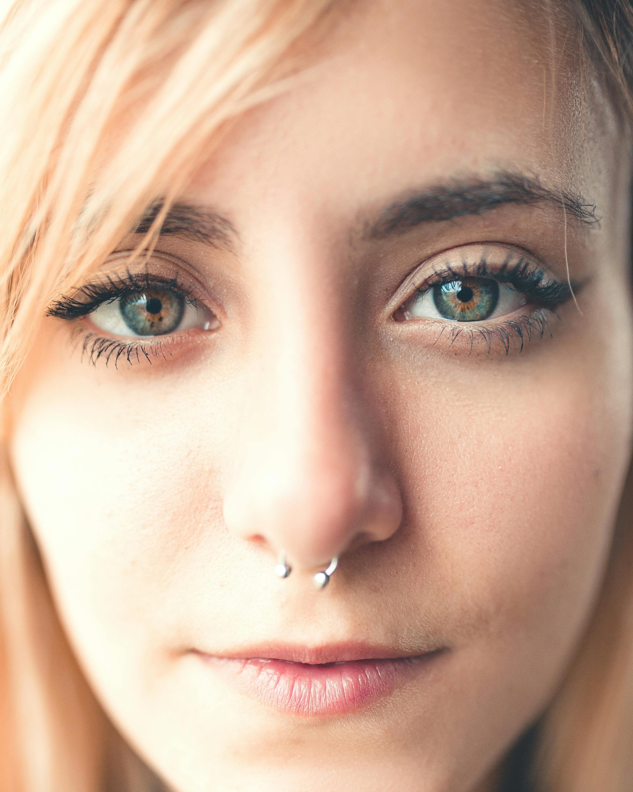 Un portrait rapproché détaillé d'une femme avec un piercing nasal et des yeux perçants, capturant la beauté naturelle.