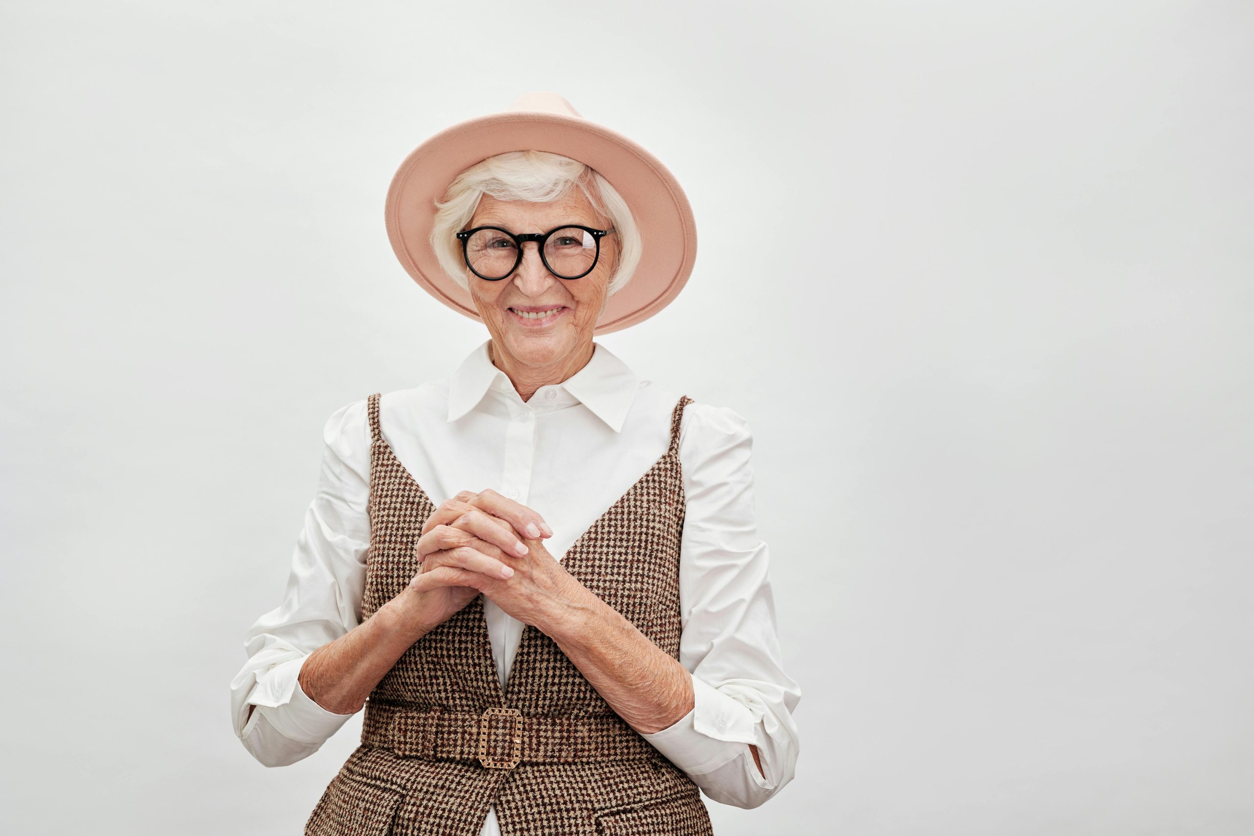 Femme senior élégante souriante avec confiance dans une tenue stylée avec chapeau et lunettes