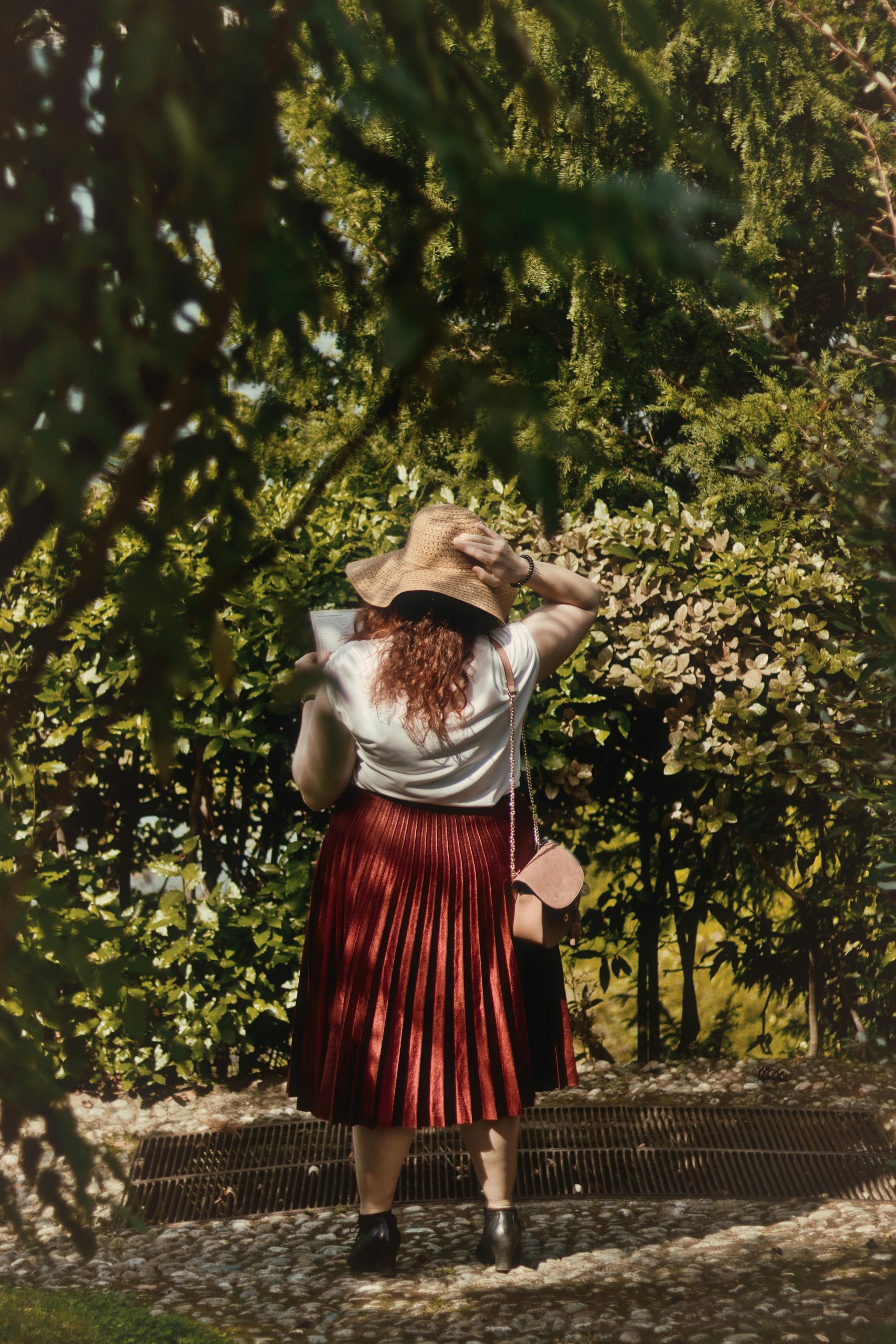 Une femme avec un chapeau de soleil et une jupe rouge profitant d'une journée ensoleillée dans un parc vert.