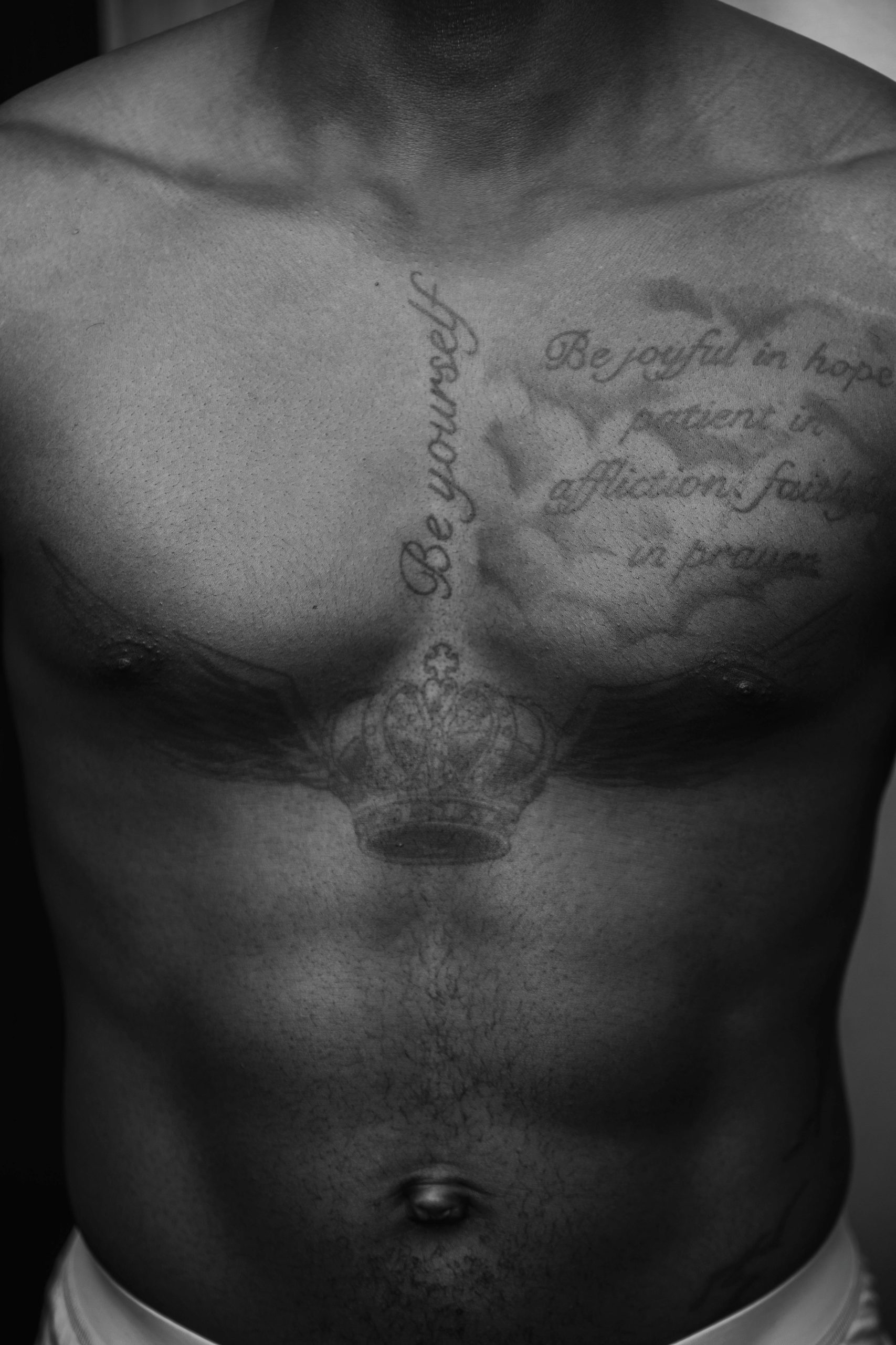 Close-up of a male torso with intricate chest tattoos in black and white. Gros plan du torse d'un homme avec des tatouages de poitrine complexes en noir et blanc.