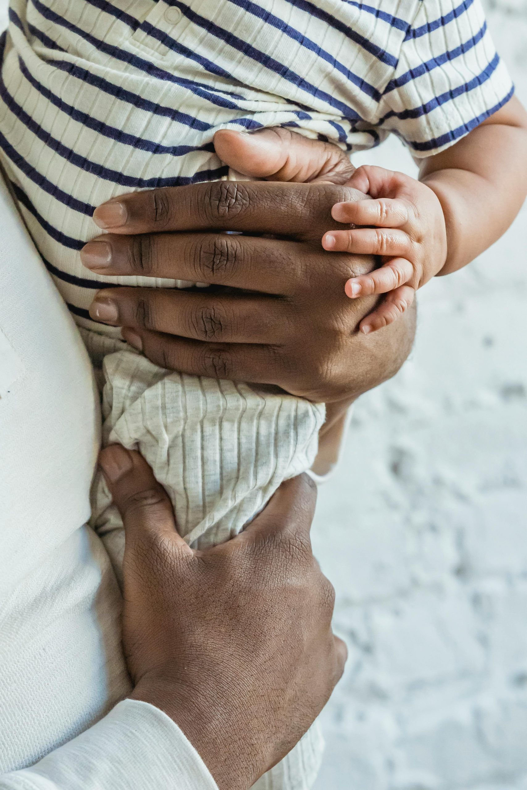 Close-up image capturing the gentle embrace between a parent and their baby, highlighting warmth and connection. Gros plan capturant l'étreinte douce entre un parent et son bébé, mettant en évidence la chaleur et la connexion.