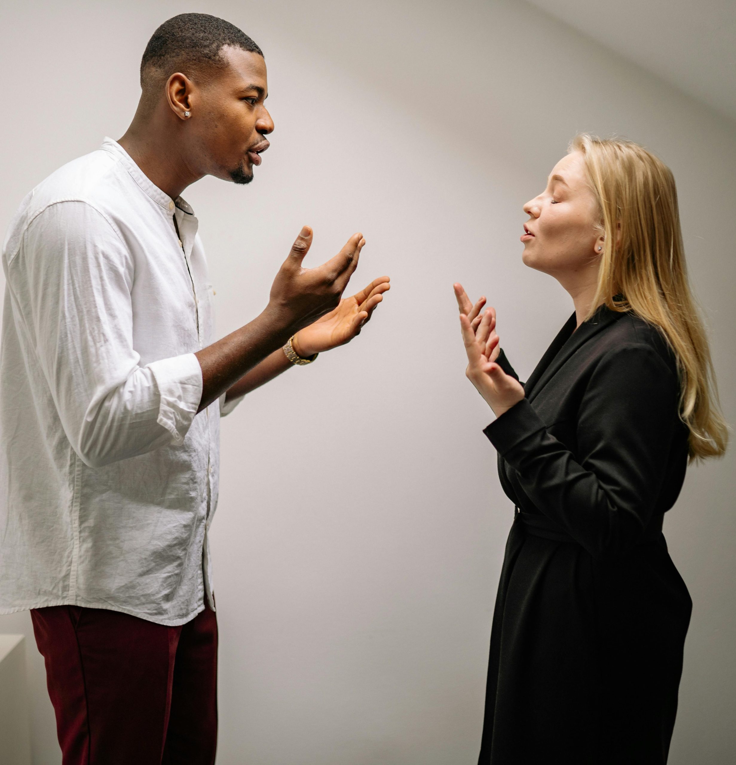A couple engaged in a heated argument indoors, expressing strong emotions and gestures. Un couple engagé dans une dispute animée à l'intérieur, exprimant des émotions et des gestes forts.