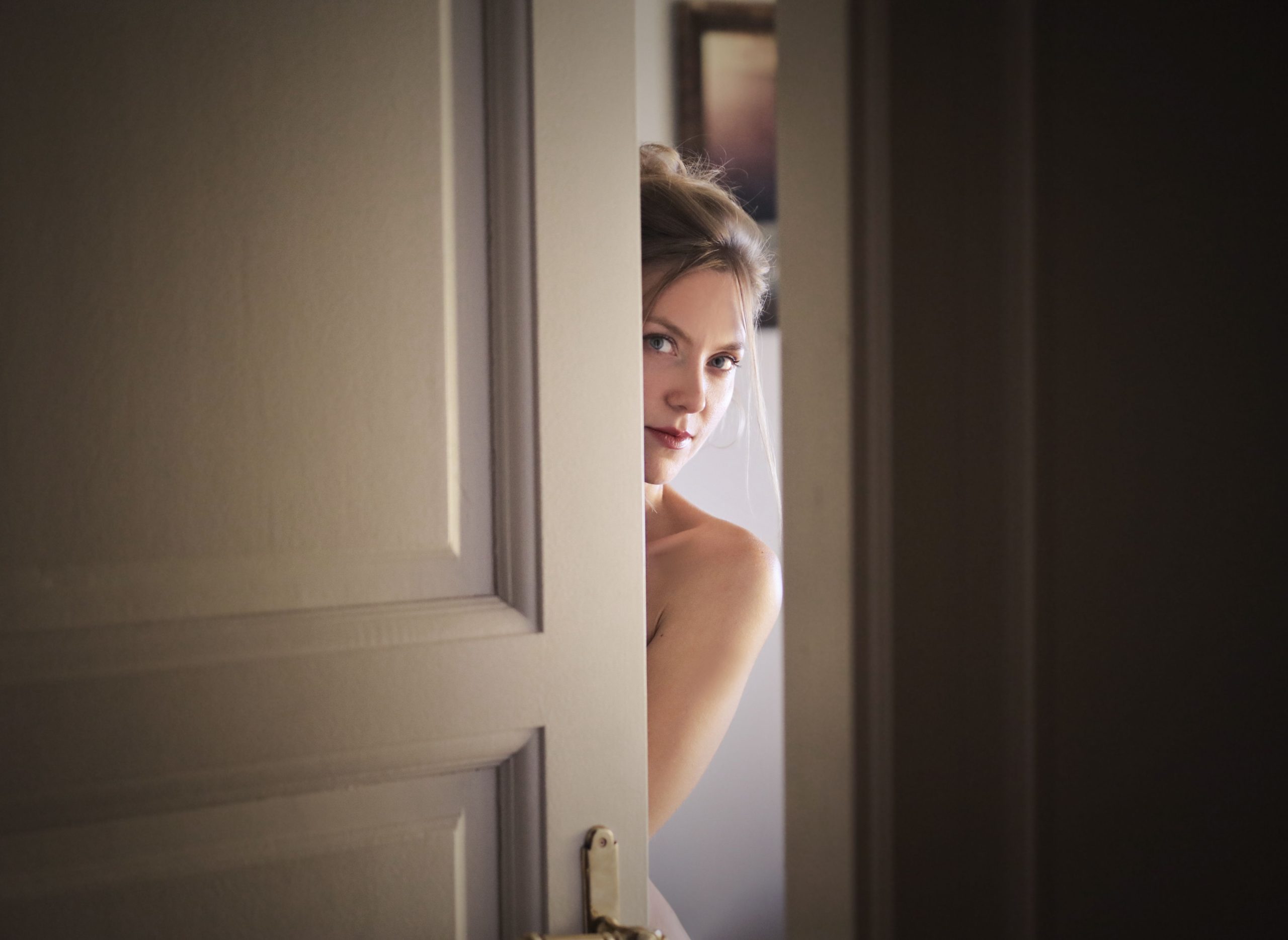 A woman peeks through a slightly opened door, creating a mysterious and intriguing atmosphere. Une femme jette un coup d'œil par une porte légèrement entrouverte, créant une atmosphère mystérieuse et intrigante.