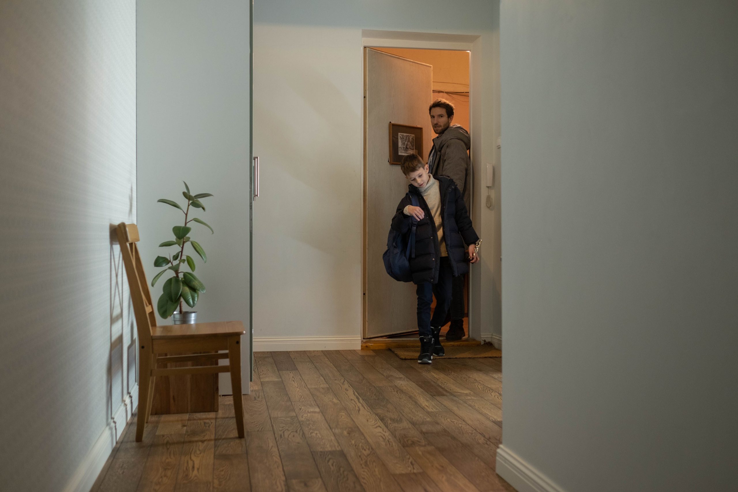 Father and son entering their cozy apartment, highlighting family togetherness and home comfort. Un père et son fils entrant dans leur appartement confortable, mettant en évidence la cohésion familiale et le confort du foyer.