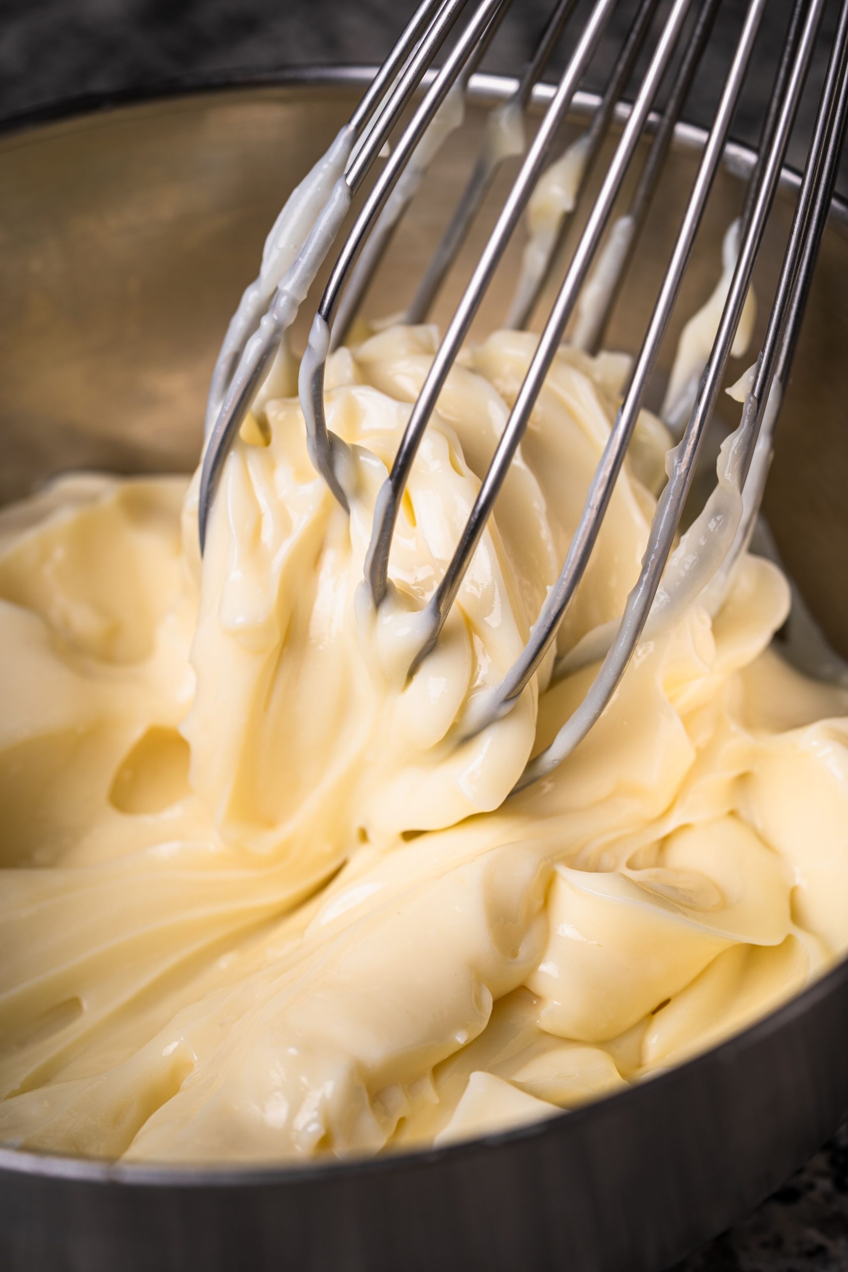 Close-up of homemade mayonnaise being whisked in a metal bowl. Gros plan de mayonnaise faite maison fouettée dans un bol en métal.
