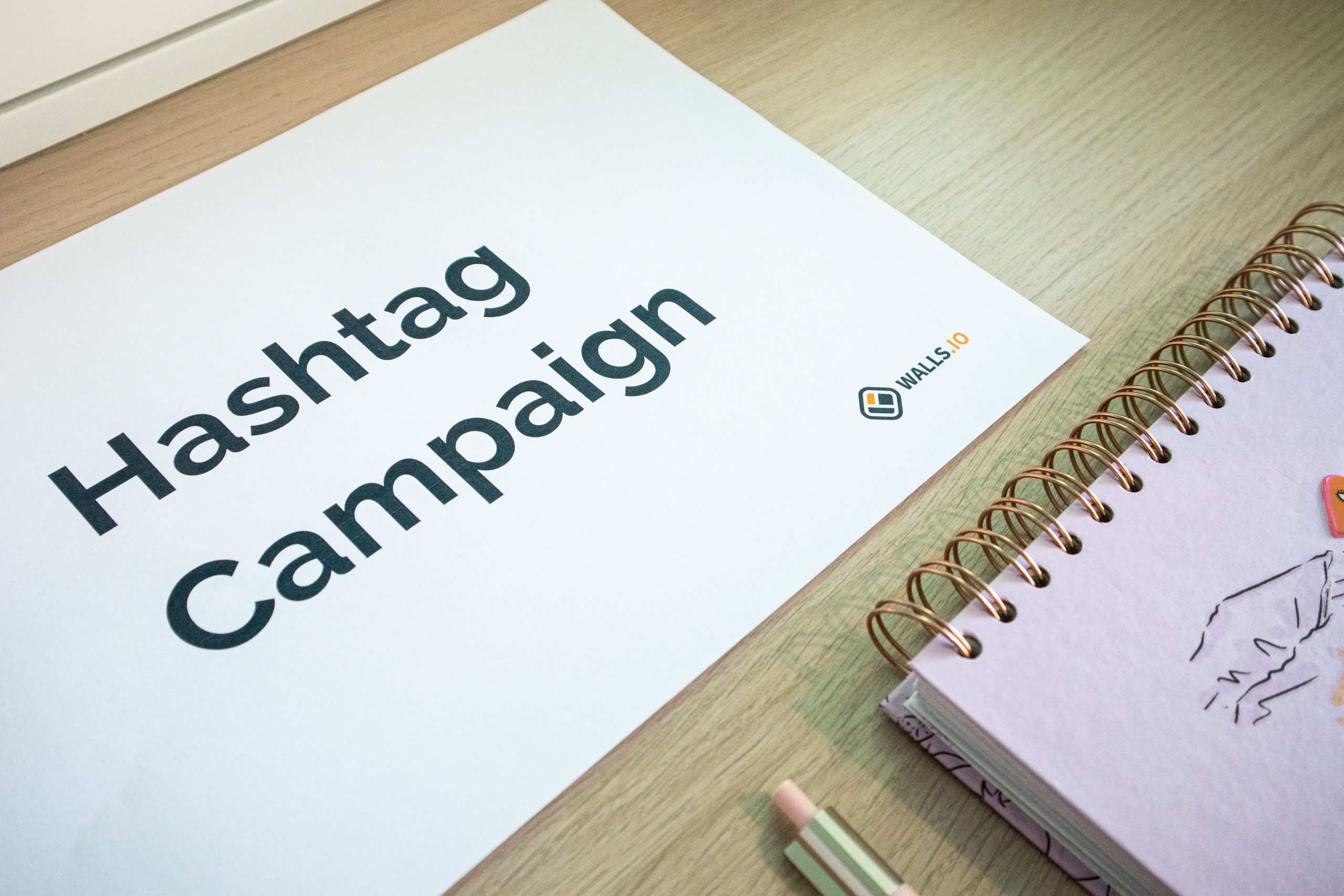 A clean office desk setup featuring hashtag campaign marketing materials and a planner. Un bureau propre et bien organisé avec des matériaux de campagne hashtag et un planificateur.