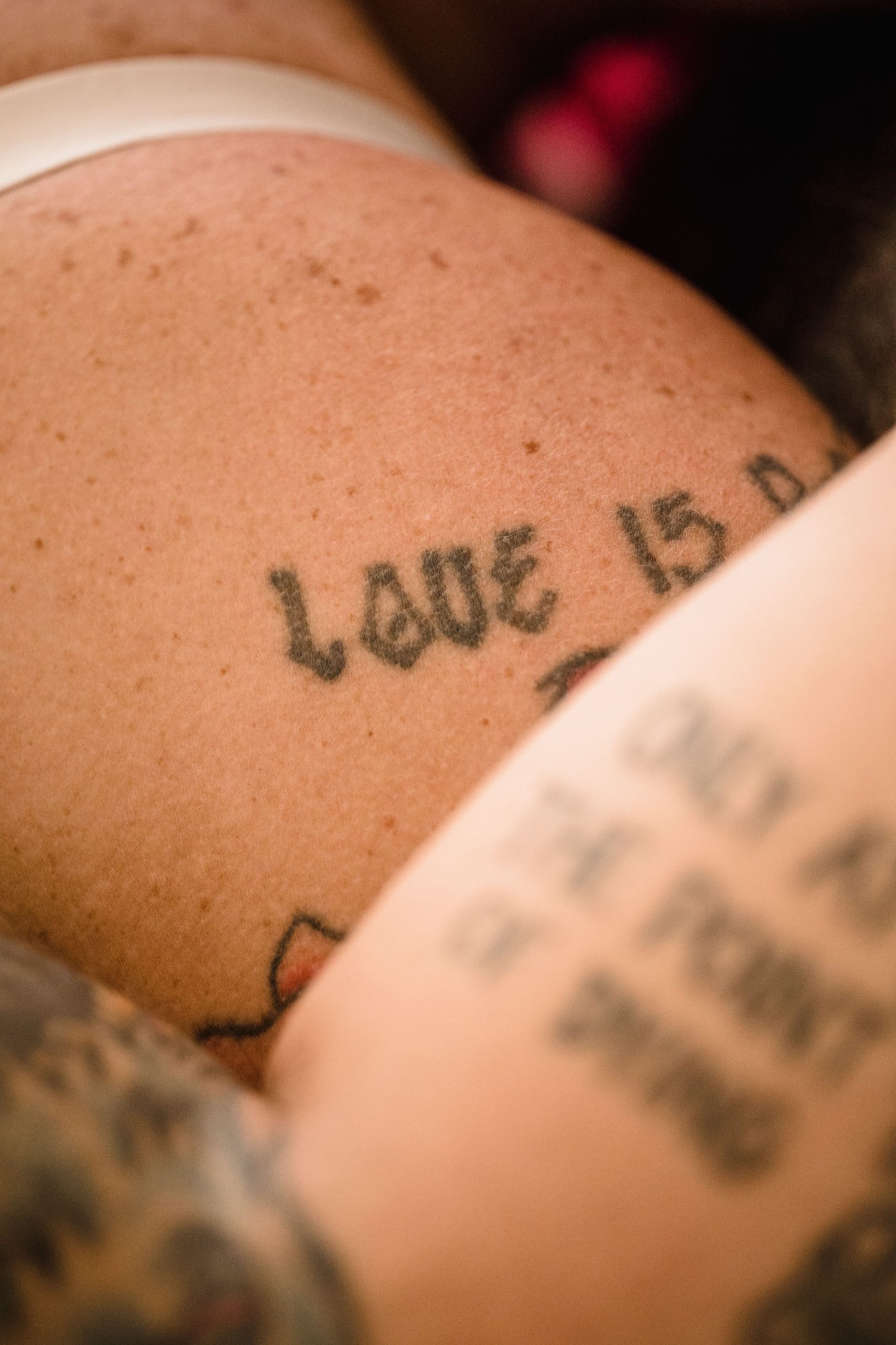 Intimate focus on a person's tattooed skin, highlighting themes of love and art. Mise au point intime sur la peau tatouée d'une personne, mettant en évidence les thèmes de l'amour et de l'art.
