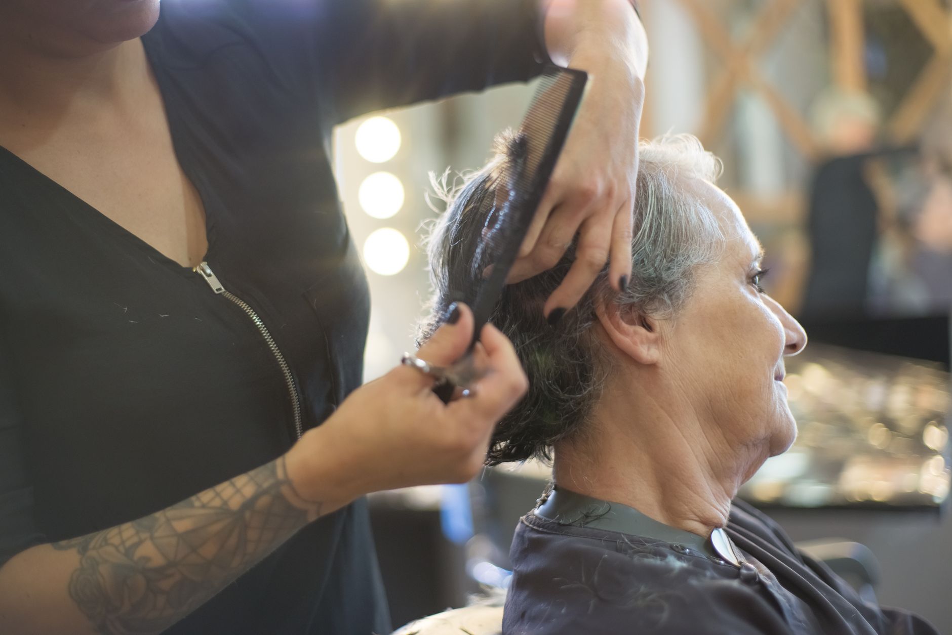 Coiffeuse peignant une coupe courte grise en salon