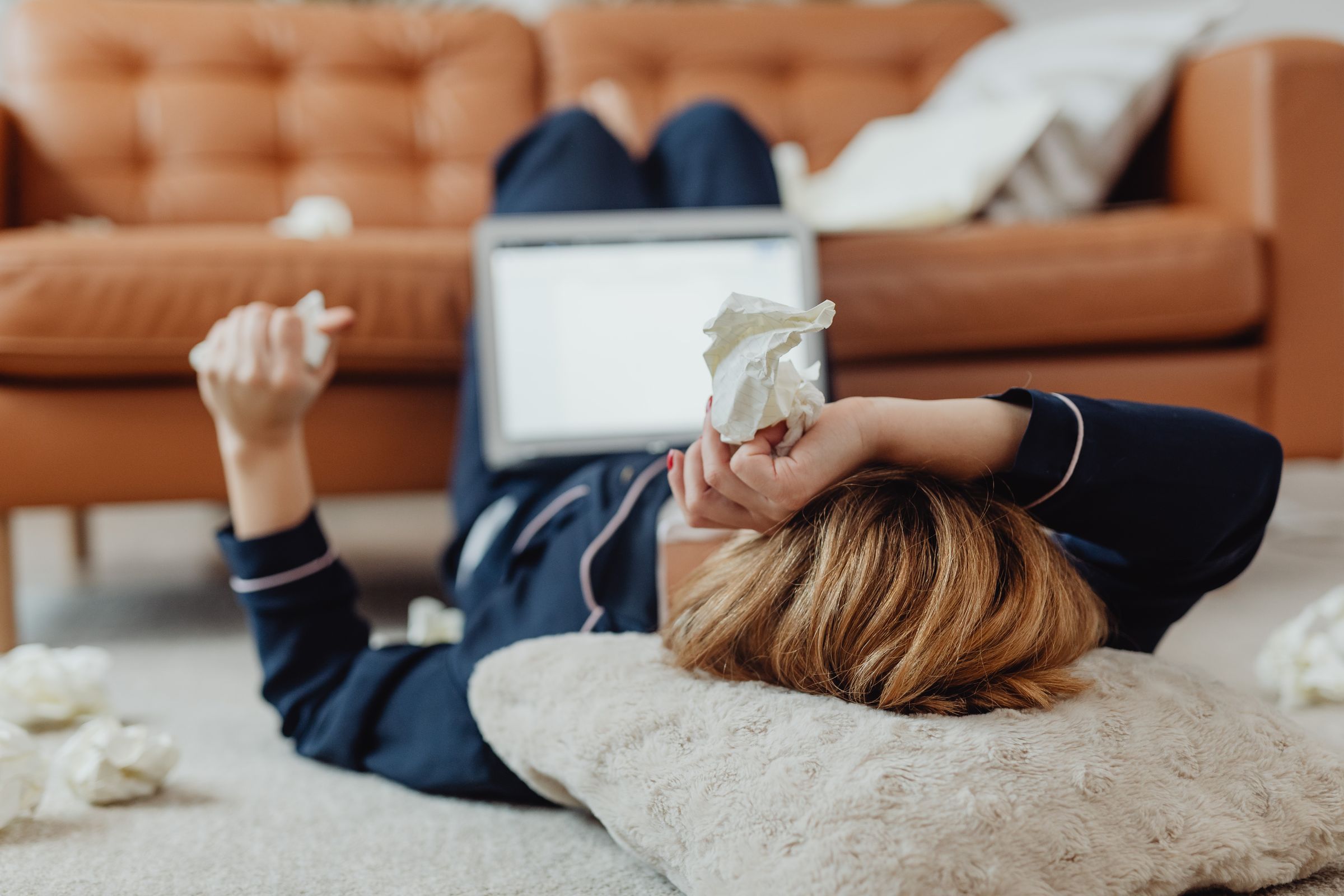 Femme enrhumée au lit entourée de mouchoirs