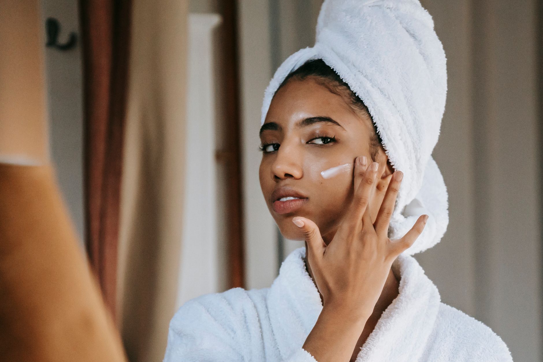 Femme appliquant une crème devant le miroir