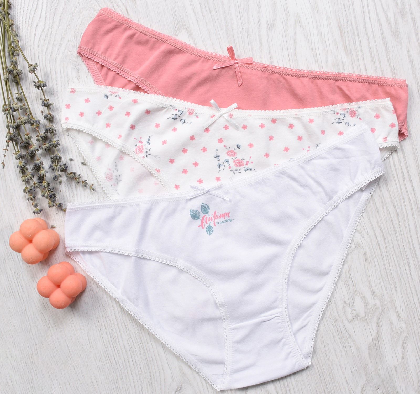 Trois culottes en coton aux couleurs pastel posées sur un fond en bois