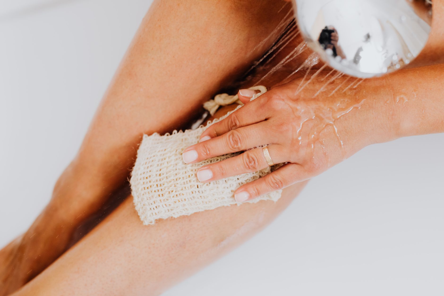 Gommage du corps avec un gant sous la douche