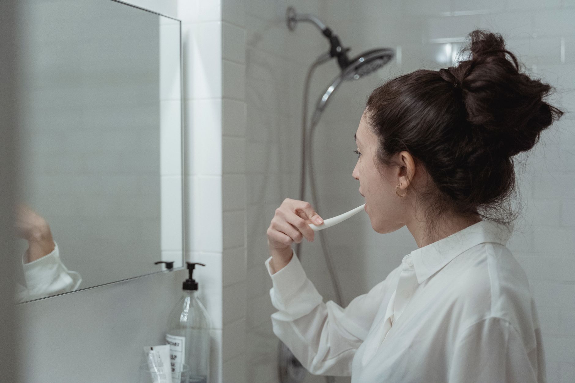 Femme qui se brosse les dents devant son miroir