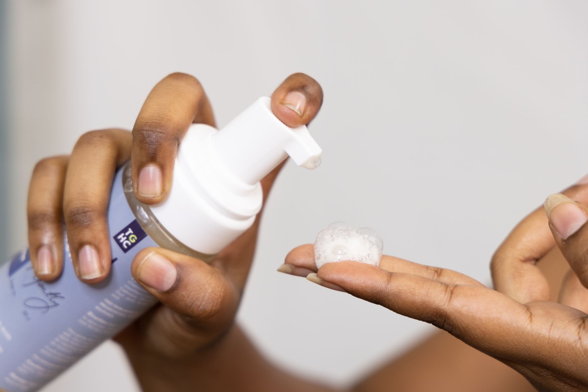 Mains versant une mousse nettoyante douce pour le visage